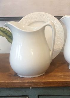 two white pitchers sitting on top of a wooden table