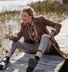 a woman is sitting on a dock with her legs crossed and smiling at the camera