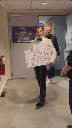 a man holding a sign with words written on it in front of two other men