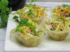 four cups filled with food sitting on top of a white plate next to some parsley