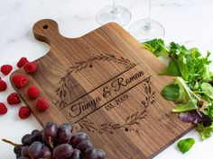 a personalized cutting board with grapes, raspberries and lettuce on it