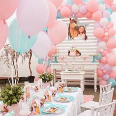 a table set up with pink, blue and white balloons in the shape of horses