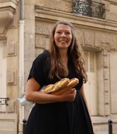 a woman in a black dress holding some bread