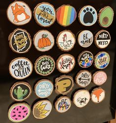 a collection of wooden magnets with different designs and words on them, sitting on a black surface