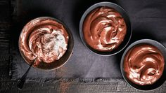 three bowls filled with chocolate pudding on top of a table