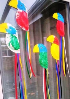 three paper plates with birds on them hanging from the side of a window sill