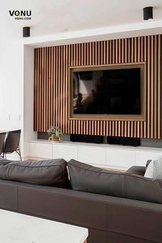 a living room with couches and a flat screen tv mounted on the wall above it