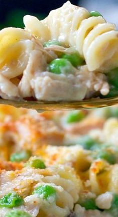 a spoon full of macaroni and cheese with peas on it is being held up