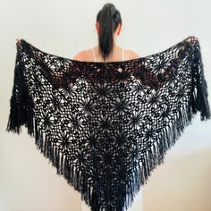 the woman is wearing a black shawl that has fringes on it's sides