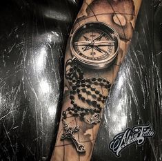 a man's arm with a compass and rosarys on it, as well as a cross