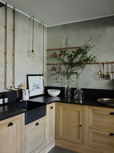 a kitchen with wooden cabinets and black counter tops, an art work hanging on the wall