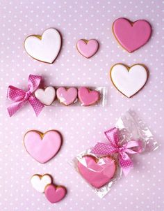 pink and white decorated cookies with bows on them are arranged in the shape of hearts