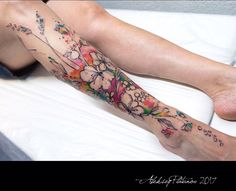 a woman's leg with flowers on it and her foot in the middle of the bed