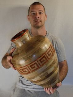 a man holding a large wooden vase in his hands