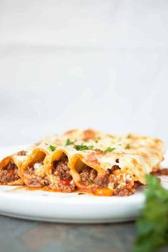 a white plate topped with lasagna covered in meat and cheese on top of a table