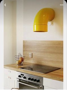 a kitchen with an oven, sink and yellow light hanging from the wall above it