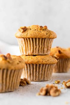 three muffins stacked on top of each other with walnuts scattered around them