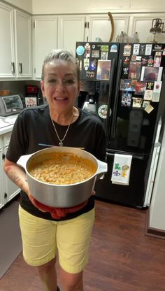 an older woman holding a large pot of food