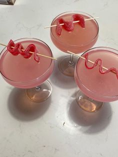 three cocktails with strawberries in them on a white counter top next to each other