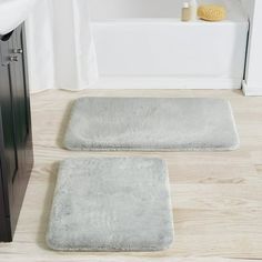 two bath mats sitting on top of a wooden floor