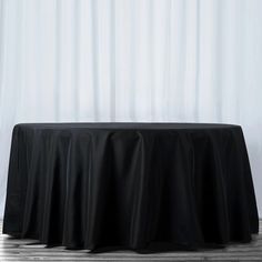 a black table cloth on top of a wooden floor next to a curtained window