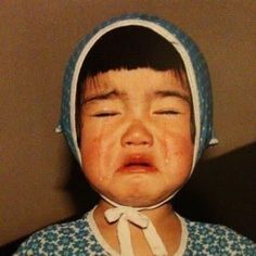 a young child wearing a bonnet and crying