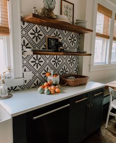 a kitchen with black and white tiles on the wall, shelves above the counter top