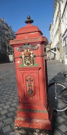 an old red phone booth sitting on the side of a road next to a bike