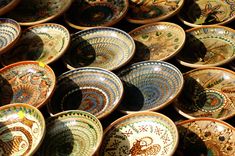 many bowls are stacked on top of each other in different colors and patterns, all with designs