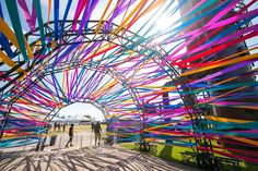 people are standing in front of an art installation with colorful ribbons on the walls and ceiling