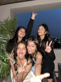 four girls posing for the camera with their hands in the air and one girl holding up her peace sign