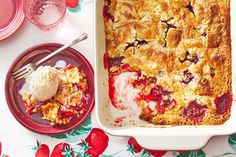 a strawberry cobbler with ice cream and strawberries on the table next to it