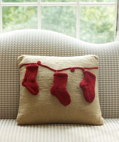 a pillow on a couch with red socks hanging from it's sides, and a window in the background