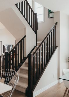 there is a glass table next to the stairs in this house with white walls and hardwood floors