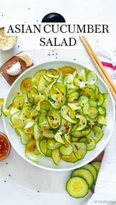 a white bowl filled with sliced cucumbers next to chopsticks and sauce