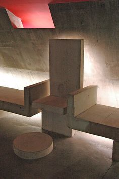 an empty concrete bench in the middle of a cement room with red light coming from above