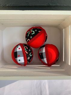 three red and black ornaments in a white box