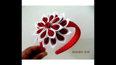 a hand holding a red and white paper flower