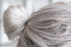 the back of a woman's head with grey hair and white top knoted up