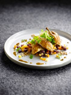 a white plate topped with food on top of a gray countertop next to a knife and fork