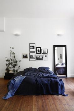 a bed sitting on top of a wooden floor next to a wall with pictures above it