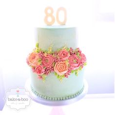 a blue cake with pink flowers on it and the number 80 written in frosting