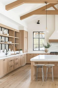 a large kitchen with wooden cabinets and white counter tops, along with two stools