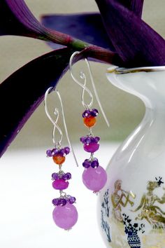 This dazzling pair of earrings in captivating shades of orange, lilac and purple quartz beads exude with iridescent splendour. The earrings cascade down in a mesmerizing design. Earring Length: 7 cms. Base Metal: 92.5 Silver Stone Type: Orange, Lilac and Purple Quartz beads Type: Danglers Occasion: Fusion of ethnic and Contemporary Care Instructions: Wipe your jewellery with a soft cloth after every use Always store your jewellery in a flat box to avoid accidental scratches Keep sprays and perfumes away from your jewellery.Do not soak your jewellery in water Purple Gemstone Party Earrings, Purple Sterling Silver Earrings For Party, Purple Gemstone Round Bead Earrings, Elegant Purple Earrings With Faceted Beads, Purple Gemstone Earrings With Round Beads, Purple Drop Earrings With Dangling Beads, Orange Faceted Beads Dangle Earrings, Vibrant Drop Earrings Jewelry Gift, Vibrant Drop Earrings For Gifts