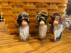 three gnomes are sitting in front of a basket on top of a wooden table