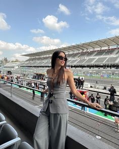 a woman is standing on the bleachers at a race track