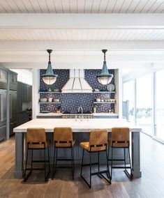 a large kitchen with an island and four stools in front of the countertop