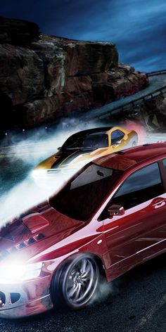 an image of two cars driving on the road in front of some rocks and water