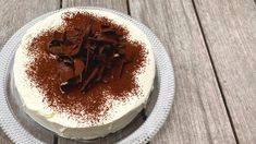 a cake with white frosting and chocolate shavings on it sitting on a plate