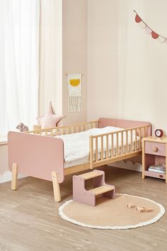 a small child's bedroom with pink furniture and accessories on the floor, including a wooden bed frame